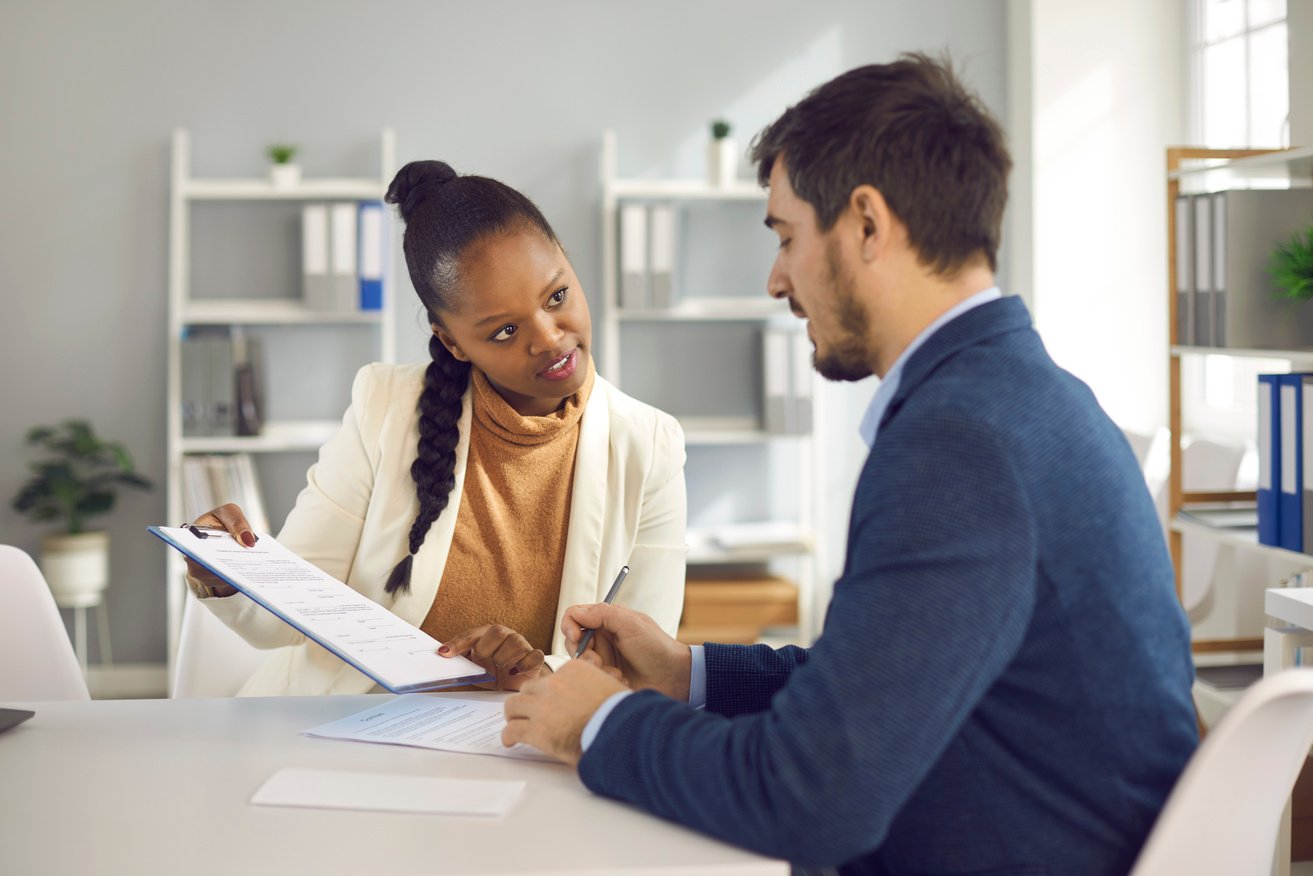 Afro American Solicitor Pointing at Insurance Contract Showing Client to Sign